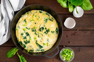 Ispanaklı omlet, yeşil soğan ve ahşap arka planda dökme demir tavada beyaz peynir. Sağlıklı kahvaltı. Kırsal tarzda. Boşluğu kopyala