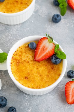 Creme brulee. Geleneksel Fransız vanilyalı kremalı tatlı üzerine karamelli şeker ve taze böğürtlen.