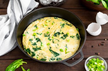 Ispanaklı omlet, yeşil soğan ve ahşap arka planda dökme demir tavada beyaz peynir. Sağlıklı kahvaltı. Kırsal tarzda. Boşluğu kopyala