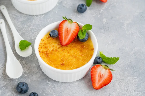 Creme brulee. Geleneksel Fransız vanilyalı kremalı tatlı üzerine karamelli şeker ve taze böğürtlen.