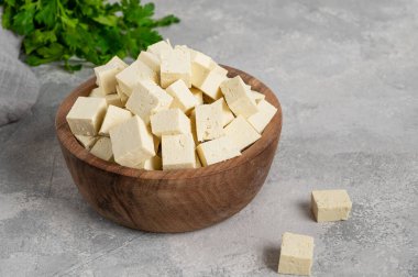 Soya fasulyesinden taze peynirli tofu, gri beton arka planda maydanozlu. Vejetaryen ürünü. Boşluğu kopyala