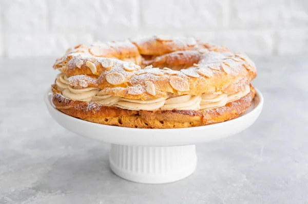 Geleneksel Fransız pastası Paris Brest, kremalı, pudra şekerli ve gri beton arka planda badem yapraklı. Boşluğu kopyala