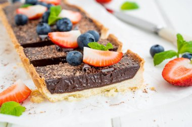 Beyaz ahşap arka planda taze yaban mersini ve çilekli çikolatalı turta. Yaz tatlısı