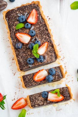 Beyaz ahşap arka planda taze yaban mersini ve çilekli çikolatalı turta. Yaz tatlısı