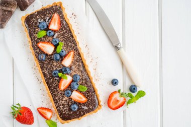 Beyaz ahşap arka planda taze yaban mersini ve çilekli çikolatalı turta. Yaz tatlısı