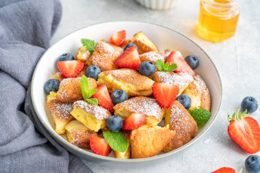 Kaiserschmarrn - gri beton arka planda taze böğürtlen ve pudra şekerli geleneksel Avustralya krep tatlısı. Güzel kahvaltı. Boşluğu kopyala