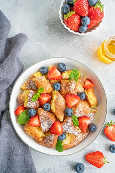 Kaiserschmarrn - gri beton arka planda taze böğürtlen ve pudra şekerli geleneksel Avustralya krep tatlısı. Güzel kahvaltı. Boşluğu kopyala