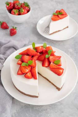 Taze çilekli fırınlanmış cheesecake ve gri beton arka planda beyaz bir tabakta nane şekeri yok. Boşluğu kopyala