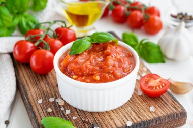 Geleneksel İtalyan marinara sosu beyaz ahşap arka planda baharat ve malzemelerle dolu bir kasede. Boşluğu kopyala