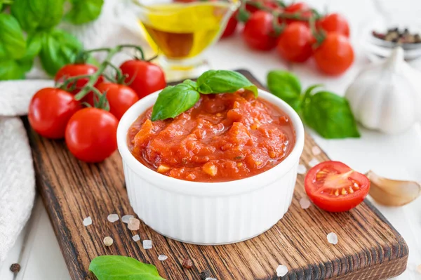 Geleneksel İtalyan marinara sosu beyaz ahşap arka planda baharat ve malzemelerle dolu bir kasede. Boşluğu kopyala