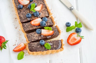 Beyaz ahşap arka planda taze yaban mersini ve çilekli çikolatalı turta. Yaz tatlısı