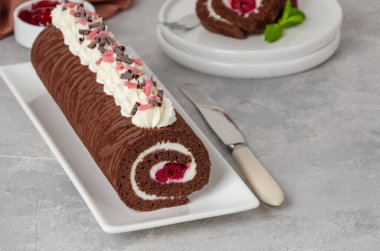 Krem şantili ve vişneli Black Forest çikolatalı kek rulosu gri bir arka planda. Boşluğu kopyala