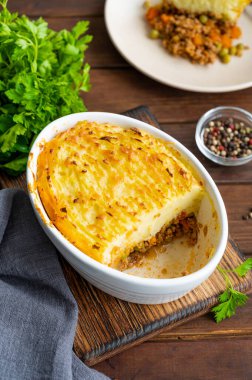 Koyu ahşap arka planda, güveç kabında ev yapımı Shepherd 's Pie. Geleneksel İngiliz yemeği, kıyma ve patates püresi.