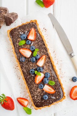 Beyaz ahşap arka planda taze yaban mersini ve çilekli çikolatalı turta. Yaz tatlısı