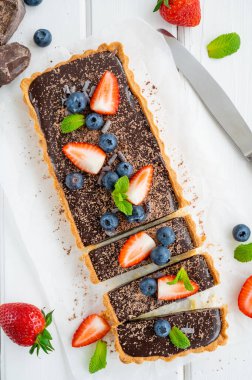 Beyaz ahşap arka planda taze yaban mersini ve çilekli çikolatalı turta. Yaz tatlısı