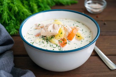 Kremalı somon çorbası, patates, havuç ve siyah ahşap arka planda bir kasede otlar. Lohikeitto çorbası. Boşluğu kopyala