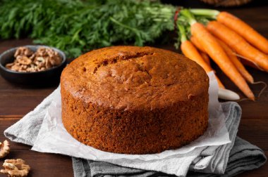 Carrot cake with cinnamon, walnuts and cream cheese frosting on a plate on a dark wooden background. Rustic style. Copy space