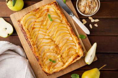Karamel soslu armut puf böreği ve ahşap zemin üzerinde badem. Lezzetli turta