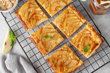 Karamel soslu armutlu börek ve gri beton arka planda badem. Lezzetli turta