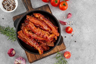 Kahvaltıda domuz pastırması, domatesli, sarımsaklı, biberiyeli ve çimento kaplı dökme demir bir tavada. Üst görünüm