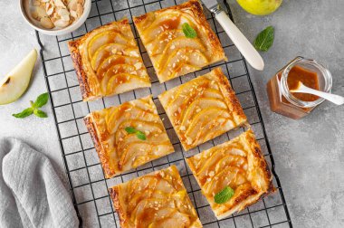 Karamel soslu armutlu börek ve gri beton arka planda badem. Lezzetli turta