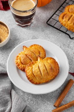 Balkabaklı mini turtalar ya da arka planda bir bardak kahveli el turtaları. Cadılar Bayramı ve Şükran Günü için geleneksel sonbahar tatlısı. Boşluğu kopyala.