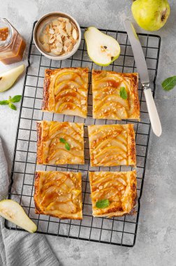 Karamel soslu armutlu börek ve gri beton arka planda badem. Lezzetli turta
