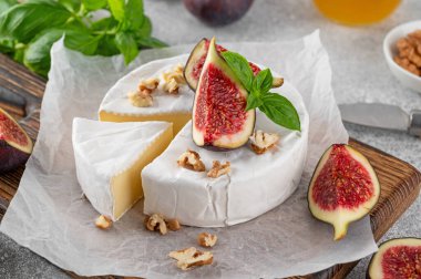 Camembert, Bree peyniri, ceviz, taze incir ve balla beton bir arka planda kesim tahtası. Şarküteri Kurulu. Üst görünüm.