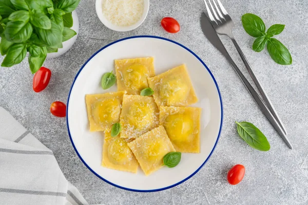 İtalyan mantısı makarna, ıspanak, ricotta, parmesan peyniri ve gri beton arka planda taze fesleğen. Üst görünüm