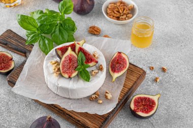 Camembert, Bree peyniri, ceviz, taze incir ve balla beton bir arka planda kesim tahtası. Şarküteri Kurulu. Üst görünüm.