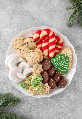 Gri beton arka planda çeşitli ev yapımı Noel kurabiyeleri olan bir tabak. Kutlama yemeği. Üst görünüm, alanı kopyala