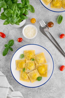 İtalyan mantısı makarna, ıspanak, ricotta, parmesan peyniri ve gri beton arka planda taze fesleğen. Üst görünüm