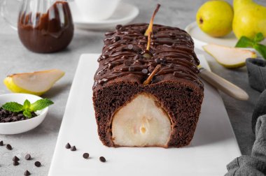 Çikolatalı turta ya da tam armutlu pasta ve gri arka planda çikolata jöleli pasta.