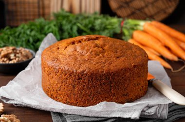 Carrot cake with cinnamon, walnuts and cream cheese frosting on a plate on a dark wooden background. Rustic style. Copy space