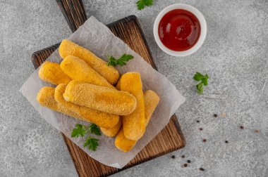 Maydanozlu ve ketçap ve hardal soslu gevrek mozzarella çubukları. Altın rengi kızarmış doku, gri arka planda iştah açıcı aperatif. Üst görünüm