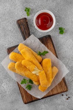 Maydanozlu ve ketçap ve hardal soslu gevrek mozzarella çubukları. Altın rengi kızarmış doku, gri arka planda iştah açıcı aperatif. Üst görünüm