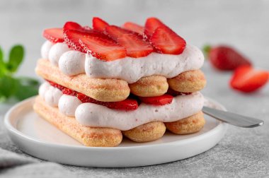 Çilekli tiramisu. İtalyan katmanlı tatlı, krema ve bisküvi ile bir tabak kahve ve beton arka planda.