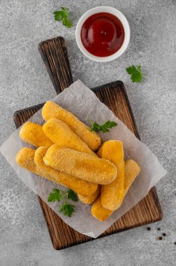 Maydanozlu ve ketçap ve hardal soslu gevrek mozzarella çubukları. Altın rengi kızarmış doku, gri arka planda iştah açıcı aperatif. Üst görünüm