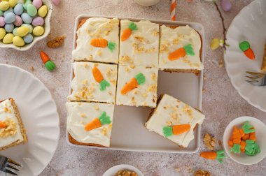 Ev yapımı Paskalya havuçlu kek ceviz ve krem peynirli krem peynirli, üstünde çikolata havucu, beyaz bir tabakta dilimlenmiş. Bayramlık tatlı. Üst görünüm, alanı kopyala.