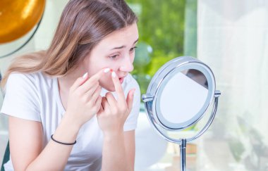 Güzel genç bir kadın yüzüne makyaj yapıyor.