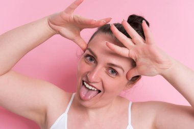 Makyajlı ve yüzünde fırça olan güzel bir kadın. Pembe üzerine izole edilmiş.