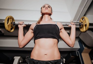 Spor salonunda halterli genç bir kadın.