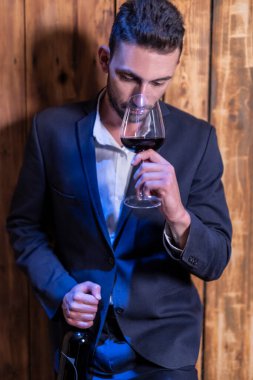 Elinde kırmızı şarap olan yakışıklı bir adam.