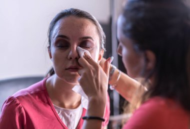 Aynaya makyaj yapan genç bir kadın.