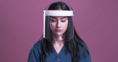 Pembe arka planda steteskobu olan genç ve güzel bir kadın.