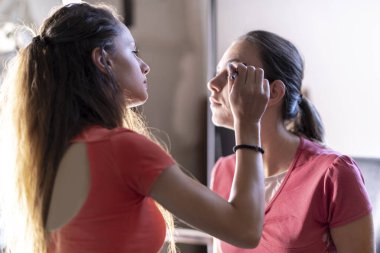 Genç ve güzel bir kadın ofiste aynaya bakıyor.