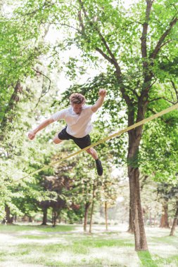 Genç adam parkta zıplıyor.