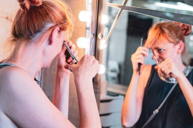 Güzel bir kadın aynaya makyaj yapıyor.