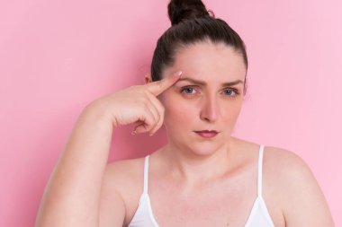 Açık arkaplanda pembe saçlı ve beyaz tişörtlü güzel bir kadın.