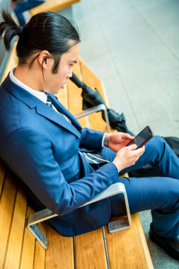 Ofiste otururken cep telefonu kullanan genç kadın.